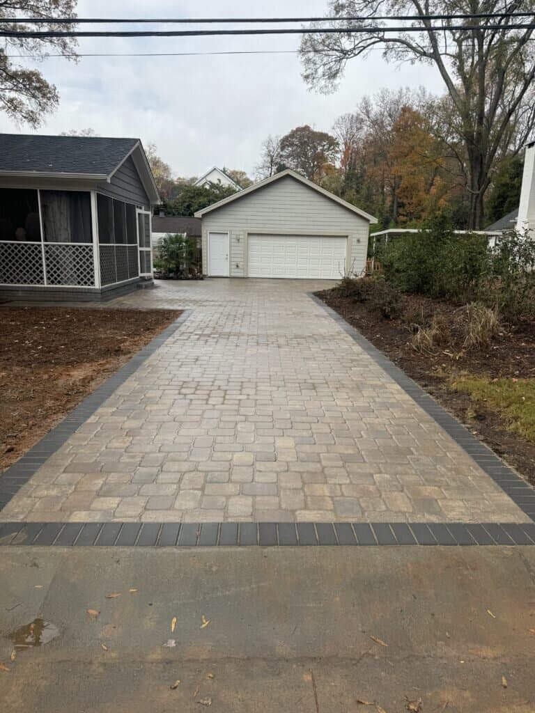 Paver driveway leading to detached garage with dark border accents