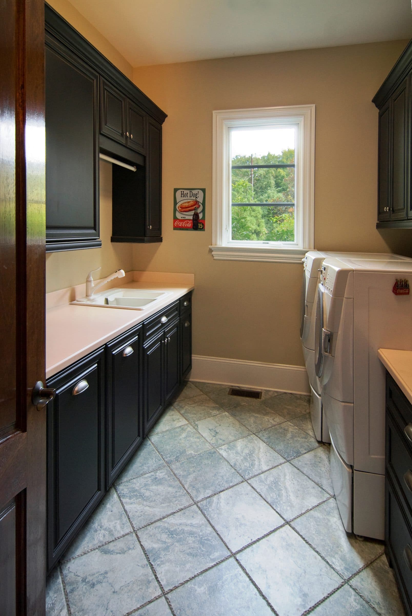 Laundry room remodel with dark custom cabinetry, utility sink, and tile flooring at Hunters Trace