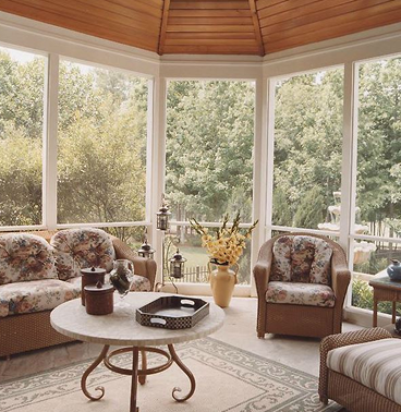 A sunroom with a gazebo-style ceiling and with three chairs inside surrounding a marble-top circular table