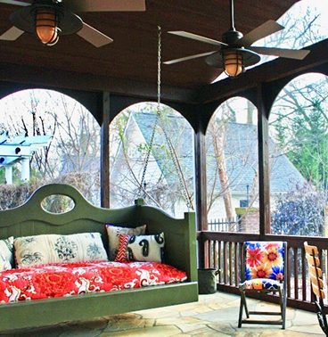 A green, cushioned loveseat-style swing on an outdoor patio