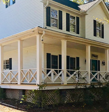 A house with white siding and a porch surrounding the outside of the lower level