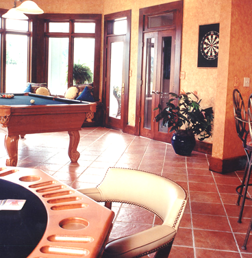 A basement room with brown tiled floor, a blackjack table, and a pool table