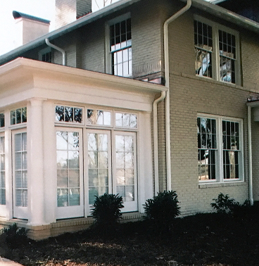 The outside of a house with white siding on the sunroom and mint green siding on the house